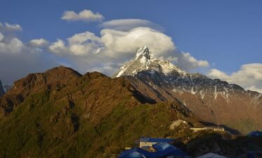 A breathtaking view of Machapuchare Mountain with its distinctive fishtail peak, seen during the Annapurna Base Camp Trek under clear blue skies.