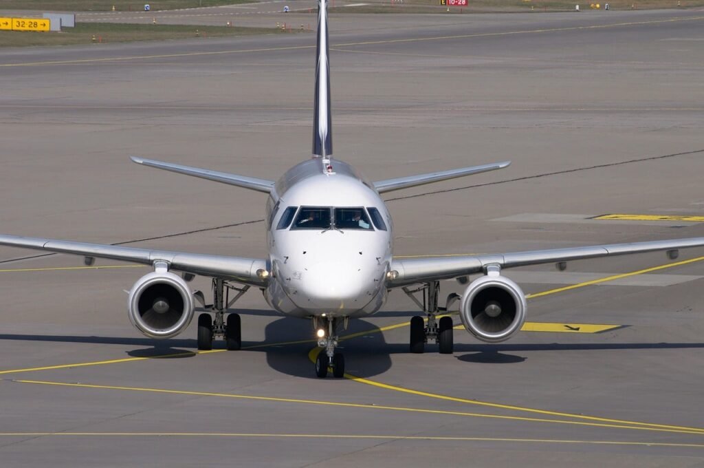 Parked commercial aircraft at airport terminal with ground service vehicles nearby.