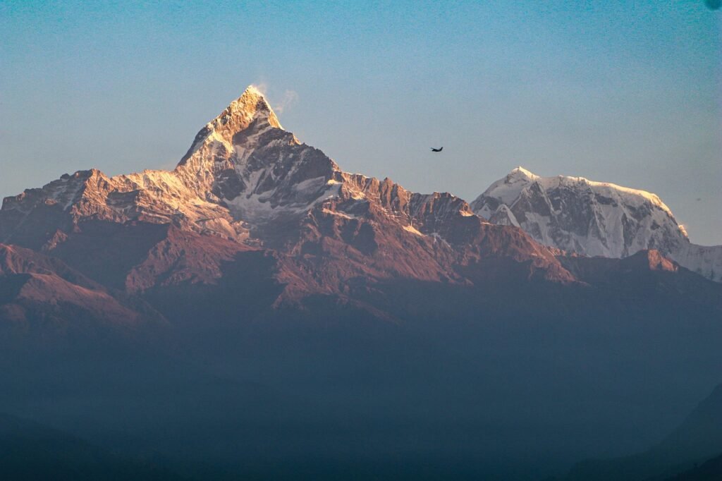 The breathtaking Machhapuchhre (Fishtail) Himalayan range with its distinctive twin peaks rising sharply against a clear blue sky.
